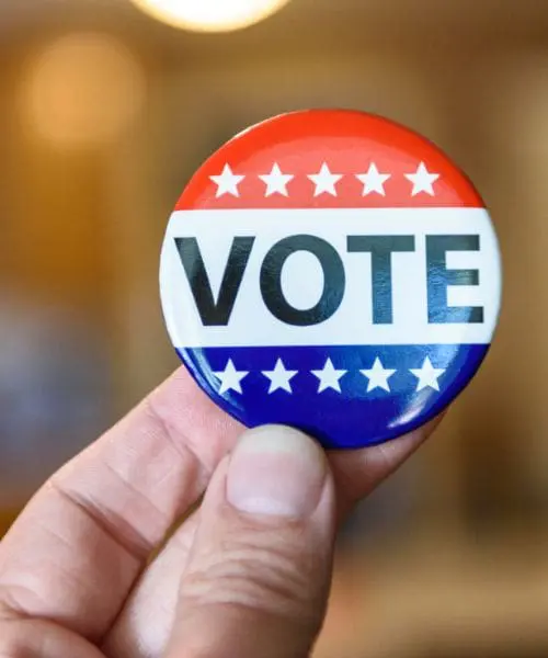 Person holding a button that says "Vote" after voting